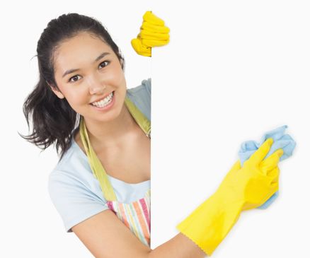 Smiling woman in apron and rubber gloves cleaning white surface